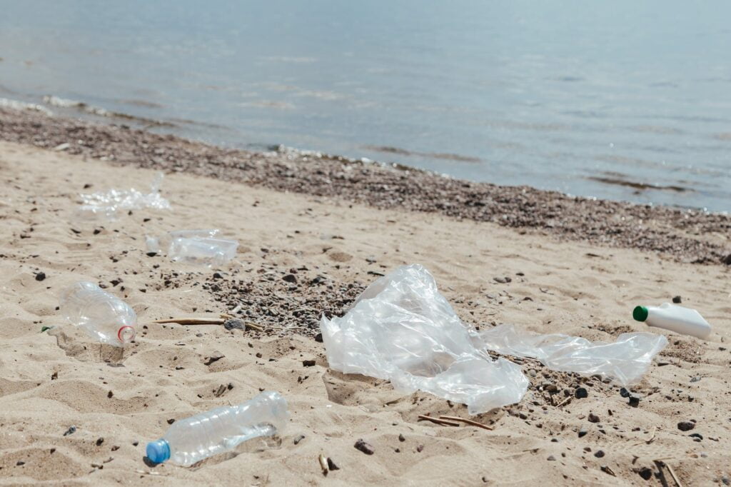 clear plastic bottle on white sand near body of water